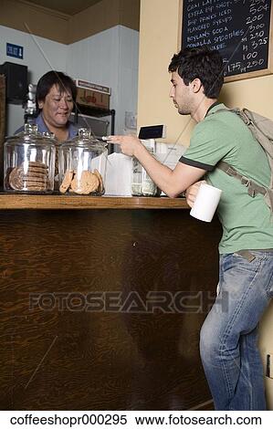 Stock Photography - A young man wearing a backpack buys a drink from a coffee shop. December 30, 2006 credit - RD / Retna Digital. Fotosearch