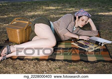 A young woman in her 20's relaxes in shorts and head scarf while reading a magazine in the park. September 1, 2006 credit - RD / Retna Digital View Large Photo Image Stock Image - A young woman in her 20's relaxes in shorts and head scarf while reading a magazine in the park. September 1, 2006 credit - RD / Retna Digital. Fotosearch
