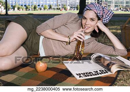 A young woman in her 20's relaxes while reading a magazine and eating a snack in the park. September 1, 2006 credit - RD / Retna Digital View Large Photo Image Stock Photography - A young woman in her 20's relaxes while reading a magazine and eating a snack in the park. September 1, 2006 credit - RD / Retna Digital. Fotosearch