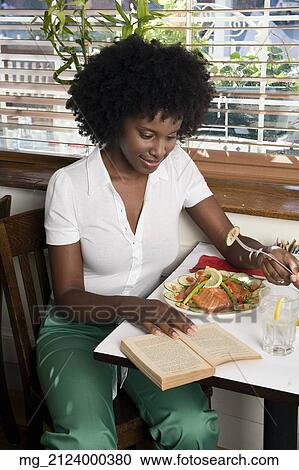 A young woman in her 20's wearing a white short sleeve top and green pants sits in a restaurant eating salmon and salad while reading a book. September 1, 2006 credit - RD / Retna Digital View Large Photo Image Stock Image - A young woman in her 20's wearing a white short sleeve top and green pants sits in a restaurant eating salmon and salad while reading a book. September 1, 2006 credit - RD / Retna Digital. Fotosearch