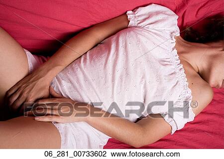 Above view mid section woman lying on a bed with her head turned and hands on her groin View Large Photo Image Stock Image - Above view mid section woman lying on a bed with her head turned and hands on her groin. Fotosearch