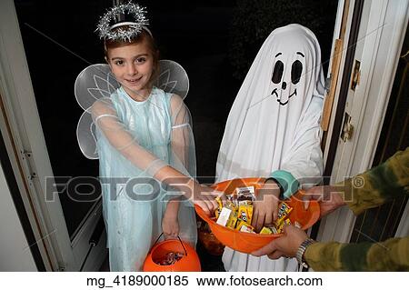 Children out on halloween. The girl is dressed as a fairy princess in a light blue gown, wings and a halo. The other child is dressed as a ghost. They are in a doorway getting thier candy treats. © Retna Digital / Retna Ltd. View Large Photo Image Stock Photography - Children out on halloween. The girl is dressed as a fairy princess in a light blue gown, wings and a halo. The other child is dressed as a ghost. They are in a doorway getting thier candy treats. © Retna Digital / Retna Ltd.. Fotosearch