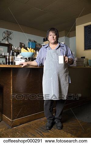 Stock Image - Coffe shop owner wearing an apron and enjoying a drink. December 30, 2006 credit - RD / Retna Digital. Fotosearch