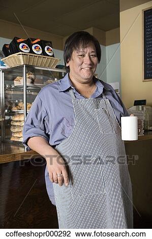 Stock Image - Coffe shop owner wearing an apron and enjoying a drink. December 30, 2006 credit - RD / Retna Digital. Fotosearch