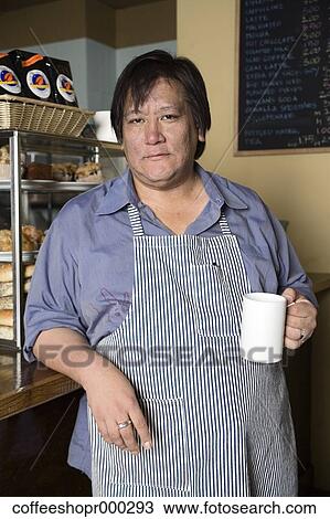 Stock Image - Coffe shop owner wearing an apron and enjoying a drink. December 30, 2006 credit - RD / Retna Digital. Fotosearch