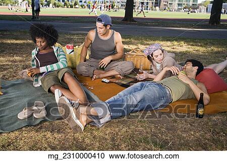 Four friends in their 20's relax while and eating a snack and playing cards in the park. September 1, 2006 credit - RD / Retna Digital View Large Photo Image Stock Image - Four friends in their 20's relax while and eating a snack and playing cards in the park. September 1, 2006 credit - RD / Retna Digital. Fotosearch