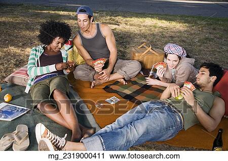 Four friends in their 20's relax while and eating a snack and playing cards in the park. September 1, 2006 credit - RD / Retna Digital View Large Photo Image Stock Image - Four friends in their 20's relax while and eating a snack and playing cards in the park. September 1, 2006 credit - RD / Retna Digital. Fotosearch