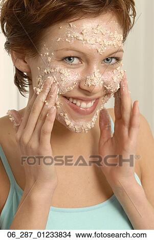 Front view head and shoulders young woman with short hair looking at camera smiling applying a face mask View Large Photo Image Picture - Front view head and shoulders young woman with short hair looking at camera smiling applying a face mask. Fotosearch