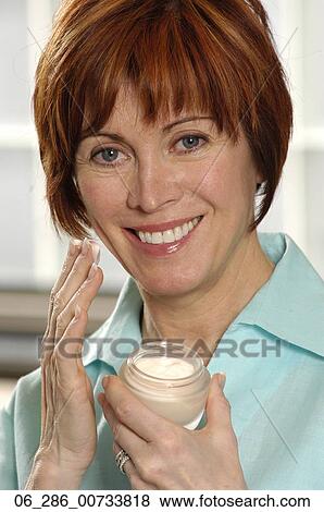Head and shoulders front view portrait woman holding a pot of moisturiser looking at camera smiling View Large Photo Image Stock Photo - Head and shoulders front view portrait woman holding a pot of moisturiser looking at camera smiling. Fotosearch