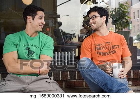 Two young men hang talk infront of a shop while enjoying a drink. September 1, 2006 credit - RD / Retna Digital View Large Photo Image Stock Image - Two young men hang talk infront of a shop while enjoying a drink. September 1, 2006 credit - RD / Retna Digital. Fotosearch