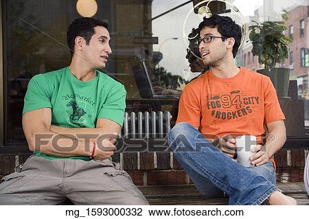 Two young men hang talk infront of a shop while enjoying a drink. September 1, 2006 credit - RD / Retna Digital View Large Photo Image Stock Image - Two young men hang talk infront of a shop while enjoying a drink. September 1, 2006 credit - RD / Retna Digital. Fotosearch
