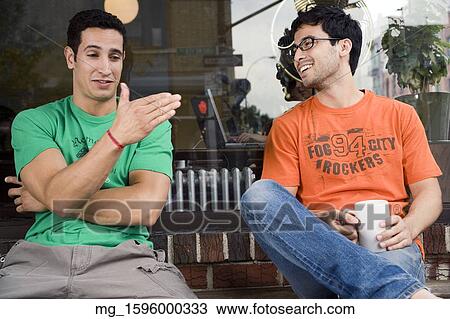 Two young men hang talk infront of a shop while enjoying a drink. September 1, 2006 credit - RD / Retna Digital View Large Photo Image Stock Image - Two young men hang talk infront of a shop while enjoying a drink. September 1, 2006 credit - RD / Retna Digital. Fotosearch