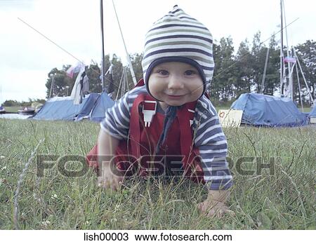 Stock Image - baby, look into the camera, full body view, grass, child, scrabble, cap. Fotosearch