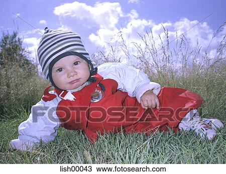 Stock Image - baby, look into the camera, full body view, grass, child, easy-going, lie. Fotosearch