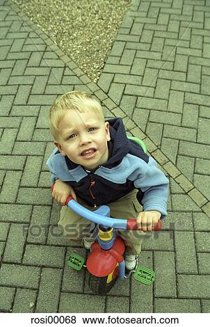 Stock Photo - long-poor, small, look up, young, infant, play, tricycle. Fotosearch