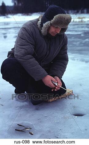 Stock Photo - Man in Winter Fishing Through Hole in Ice. Fotosearch