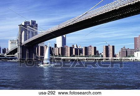 Stock Image - Yacht Passing under the Brooklyn Bridge New York. Fotosearch