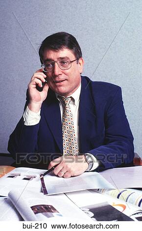 Businessman at Desk Talking on Mobile Phone UK View Large Photo Image Stock Image - Businessman at Desk Talking on Mobile Phone UK. Fotosearch