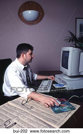 Businessman with Newspaper Working at Computer UK View Large Photo Image Stock Image - Businessman with Newspaper Working at Computer UK. Fotosearch