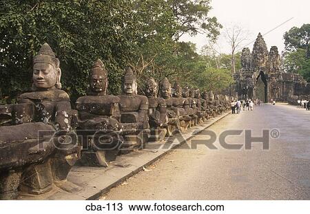 Stock Image - Line of God Statues South Gate Angkor Thom Cambodia. Fotosearch