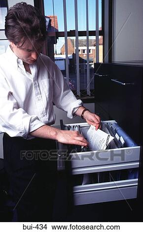 Picture - Man Looking through Filing Cabinet. Fotosearch