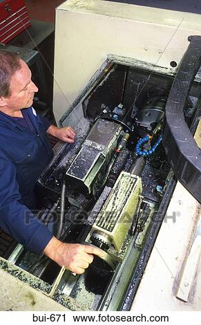 Stock Image - Man Maintaining Milling Machine in Factory. Fotosearch