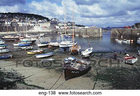 Stock Photo - Boats at Low Tide Mousehole Harbour Cornwall England. Fotosearch