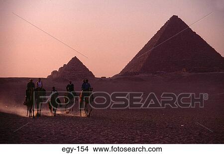 Picture - People Riding by Pyramids at Dusk Egypt. Fotosearch