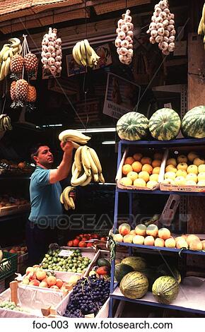Stock Image - Shopkeeper Hanging out Display of Fruit Portugal. Fotosearch