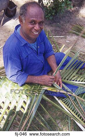 Stock Photograph - Smiling Man Weaving Palm Leaves Fiji. Fotosearch