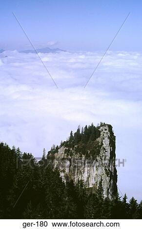 Stock Image - Tree Covered Outcrop against Cloud Alps Germany. Fotosearch