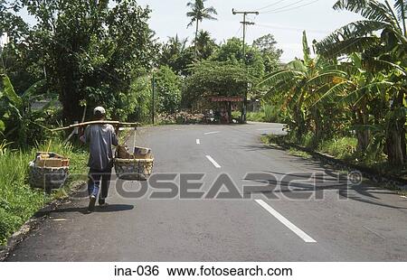 Stock Photograph - Man Carrying Baskets with Yoke Seminyak Bali. Fotosearch