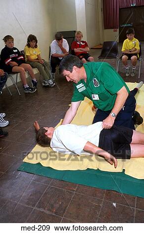 Man Teaching Recovery Position to School Children View Large Photo Image Stock Photo - Man Teaching Recovery Position to School Children. Fotosearch