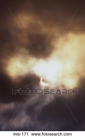 Stock Image - Partial Eclipse Through Clouds. Fotosearch