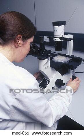 Stock Photography - Technician Examining Test Vials Using Microscope UK. Fotosearch