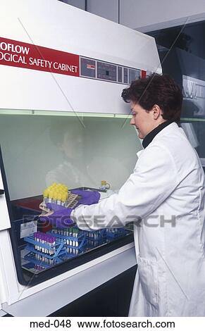 Stock Photo - Technician Handling Test Vial in Safety Cabinet. UK. Fotosearch