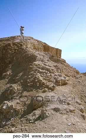 Picture - Man Using Video in Desolate Landscape Israel. Fotosearch