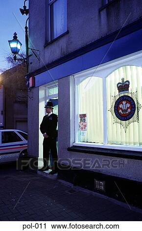 Stock Image - Policeman Standing in Station Doorway at Night. Fotosearch