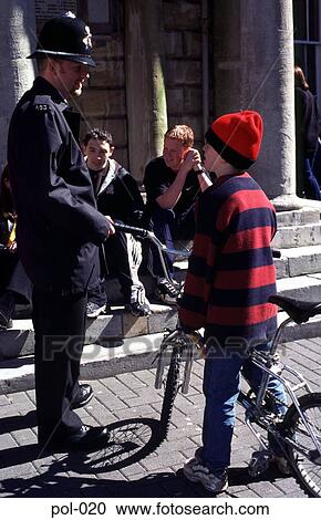 Stock Image - Policeman Talking to Boy on Bicycle Wales UK. Fotosearch