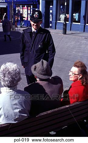 Stock Photo - Policeman Talking to Old Women on Bench Wales UK. Fotosearch