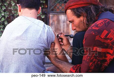 Stock Photo - Young Man being Tattooed Rome Italy. Fotosearch