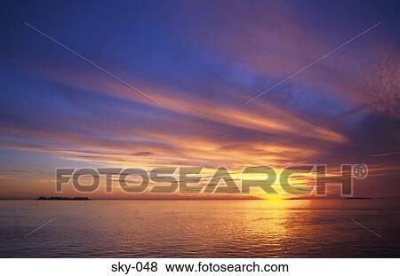 Stock Photo - Cirrus Clouds in Sky at Sunset over Sea. Fotosearch