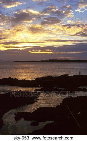 Stock Image - Clouds over Rocky Beach at Dusk. Fotosearch