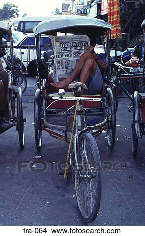 Picture - Man Reading a Newspaper in a Rickshaw Thailand. Fotosearch