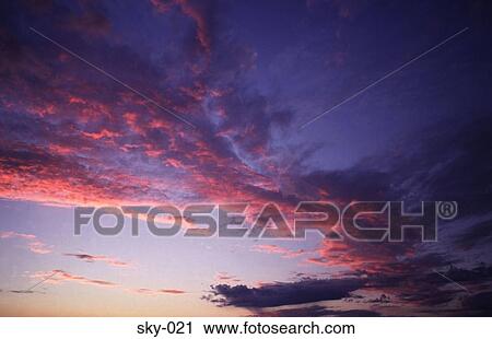 Stock Image - Pink Highlighted Cirrus Clouds in the Sky at Sunset. Fotosearch