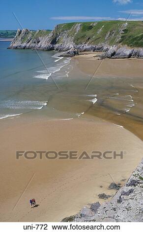 Stock Image - Couple on Empty Beach Three Cliffs Bay Wales. Fotosearch