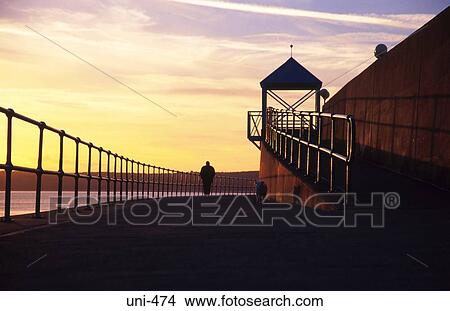 Man and Sea Defences against Sunset Swansea Wales View Large Photo Image Picture - Man and Sea Defences against Sunset Swansea Wales. Fotosearch