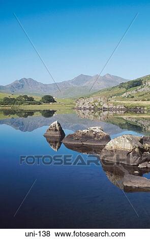 Rocks and Mountains Reflected in Still Lake Wales UK View Large Photo Image Stock Photo - Rocks and Mountains Reflected in Still Lake Wales UK. Fotosearch