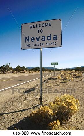 Stock Image - Welcome to Nevada Sign on Desert Road USA. Fotosearch