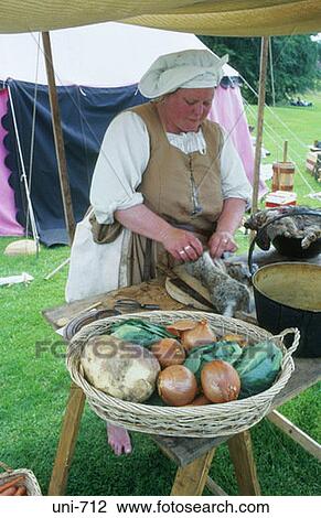 Stock Image - Woman in Medieval Costume Skinning Rabbit UK. Fotosearch